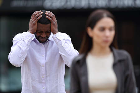 Front view portrait of an interracial couple breaking up in the street