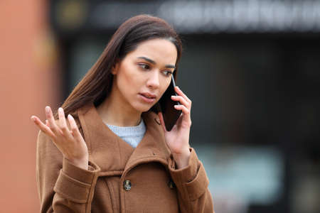 Angry woman in the street talking on mobile phone complainingの写真素材