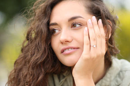 Confident woman showing engagement ring looking at side after proposalの写真素材
