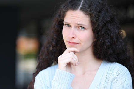 Portrait of a suspicious woman looking at camera in the street