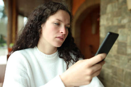 Woman checking smart phone sitting in a restaurant interiorの写真素材