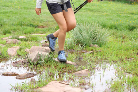 Close up of a hiker legs crossing river in the mountain