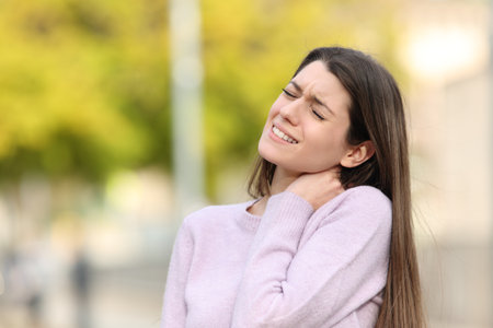 Teen complaining due neck ache standing in a parkの写真素材