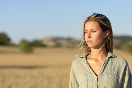 Serious woman in a field looking at sideの写真素材
