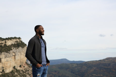 Happy black man contemplating nature standing in the mountainの写真素材