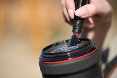 Close up of a photographer hand cleaning lens outside in a parkの写真素材