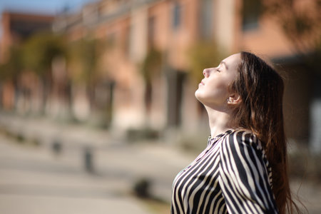 Profile of a woman breathing fresh air a sunny day in a residential areaの写真素材