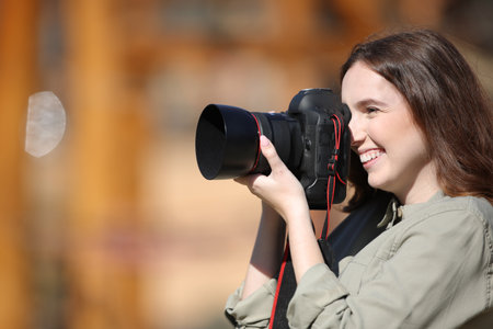 Side view portrait of a happy photographer taking photos outdoorの写真素材