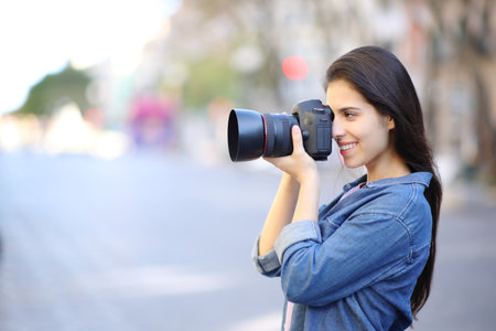 Side view portrait of a happy photographer taking photos in the streetの写真素材
