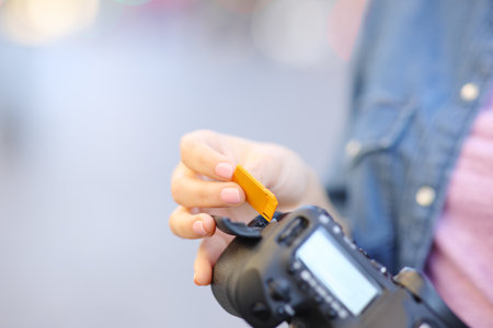 Close up of a photographer hand insterting sd card on camera in the streetの写真素材