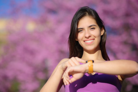 Front view portrait of a happy woman looking at camera using smartwatchの写真素材