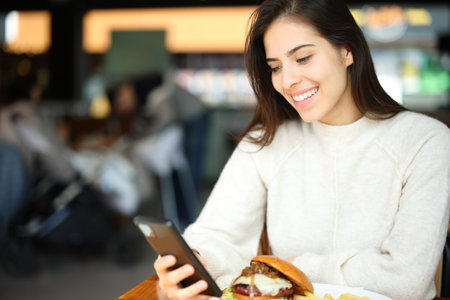 Customer checking smart phone sitting in a restaurant