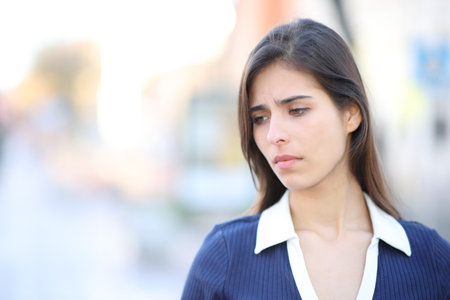 Sad woman complaining looking down walking in the streetの写真素材