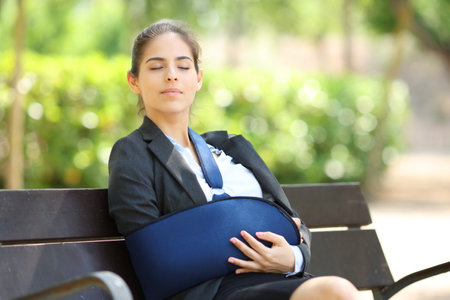 Convalescent businesswoman resting sitting on a bench in a parkの写真素材