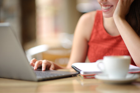 Close up of a student hand using laptop in a terraceの写真素材
