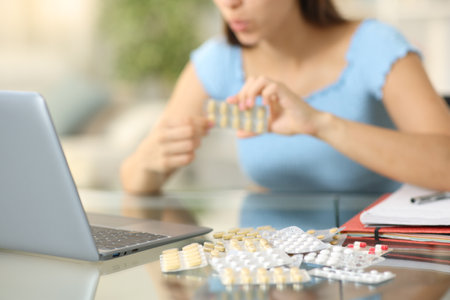 Closeup of a student taking a lot of pills at homeの写真素材