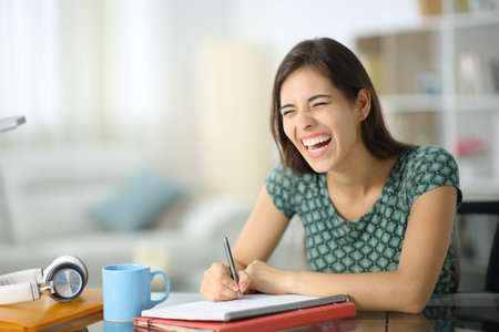 Happy student laughing loud studying at homeの写真素材