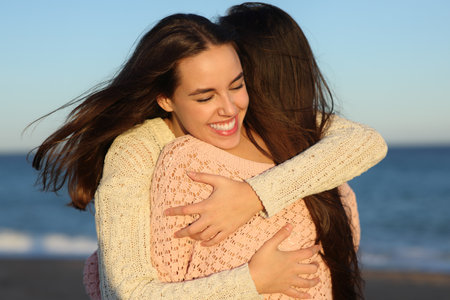 Two happy friends hugging affectionate at sunset on the beachの写真素材