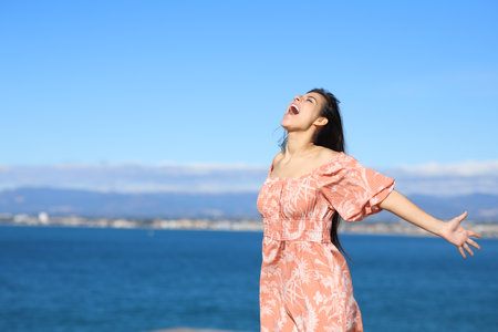 Excited woman screaming to the air on the beachの写真素材
