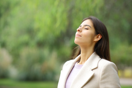 Relaxed woman breathing fresh air in a park in winter seasonの写真素材