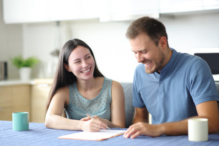Happy roommates checking contract ready to sign it in the kitchen at homeの写真素材