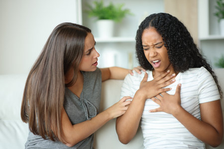 Scared woman trying to help her friend who is choking at homeの写真素材