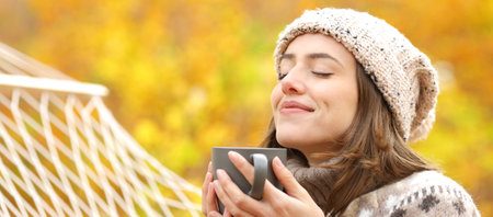 Banner of a happy woman drinking coffee and breathing fresh air in autumn forestの写真素材