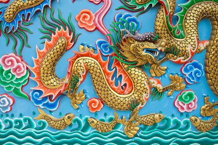 The golden dragon statue on blue wall at chinese templeの写真素材