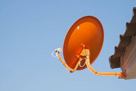 The orange satellite dish with the blue sky backgroundの写真素材