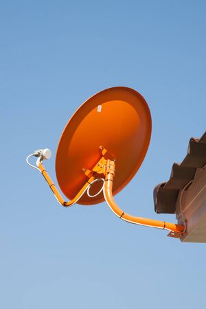 The orange satellite dish with the blue sky backgroundの写真素材