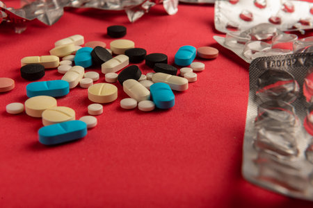 many colored pills and their empty containers on a red background. medicine concept. (series).の写真素材