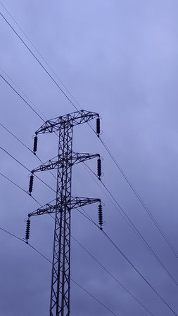 Towers and power lines of high and medium voltage with a cloudy sky in the background.の写真素材