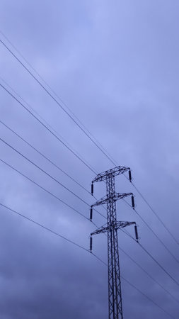 Towers and power lines of high and medium voltage with a cloudy sky in the background.の写真素材