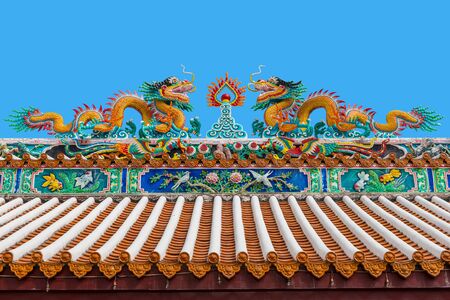 Two chinese dragons statue chasing the flaming pearl on the roof of the temple with blue sky in...