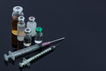 Various type of vaccine bottles and the syringes isolated on grey backgroundの写真素材