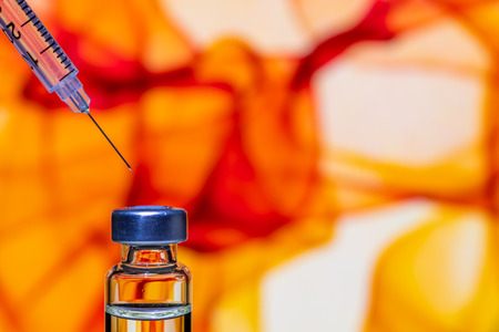 A syringe with the needle point to the vaccine vial on the colorful abstract backgroundの写真素材