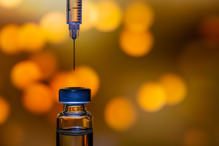 A syringe with the needle point to the vaccine vial on the colorful abstract backgroundの写真素材