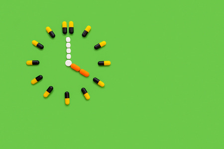 The pills clock isolated on green backgroundの写真素材