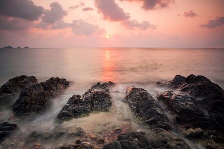 A dramatic scenic landscape shot of the rocks in the ocean with beautiful sky and mountain in background, on a tropical island, shooting in long exposure mode during summer time, Samui island Thailandの写真素材