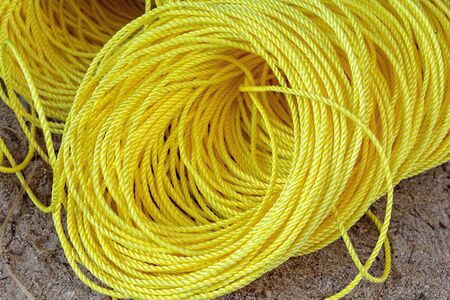 Coil of yellow synthetic rope on groundの写真素材