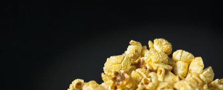 Delicious popcorn with caramel in bowl on black color background