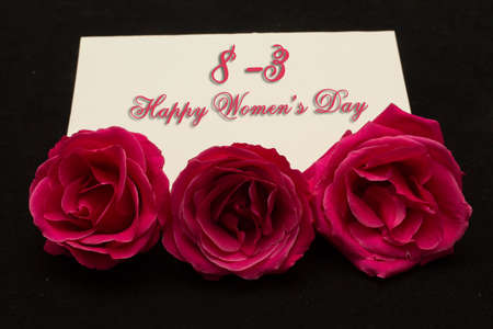Happy Womans Day March 8th written on white card with red rosesの写真素材