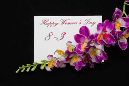 Happy Womans Day March 8th written on white card with red rosesの写真素材