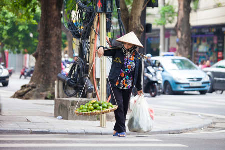 Hanoi, Vietnam - November 21, 2019: Street vendors are hurriedly cycling across the street to find customers in the small neighborhood in Hanoi, Vietnamのeditorial素材