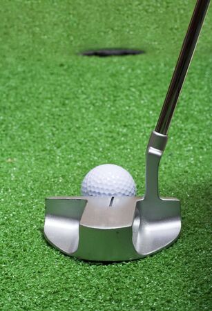A putter lines up on the green to sink a golf ball.の写真素材