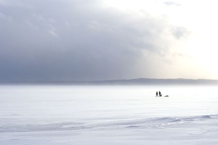 A couple walk with their pet in a winter landscape.の写真素材
