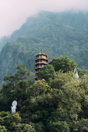 Portrait view of Xiangde Temple from valley below with sharp cliffs behind and misty sky.の写真素材
