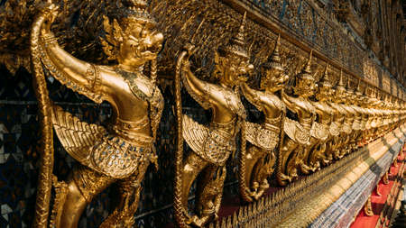 Line of ornate, golden garuda statues hanging on wall of The Emerald Buddha temple, Wat Phra Kaew, Grand Palace, Bangkok, Thailand.のeditorial素材