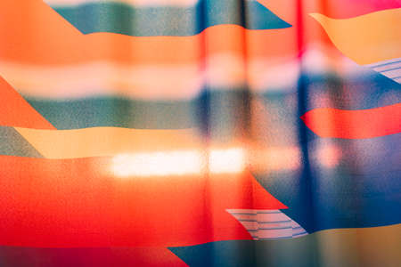 Thin, shining cloth sheet with neon, red, blue and yellow color with light shining from behind.の写真素材