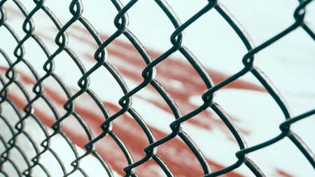 Metal chain-link fence with ice on it and a snowy ground in the background.